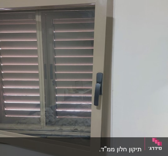 תריסים חומים עם ידית שחורה על חלון פתוח